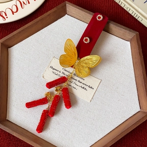 Détail de pince à cheveux en velours rouge avec papillon doré et glands