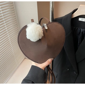 Detail einer braunen herzförmigen Wildledertasche mit einem weichen weißen Bommelanhänger