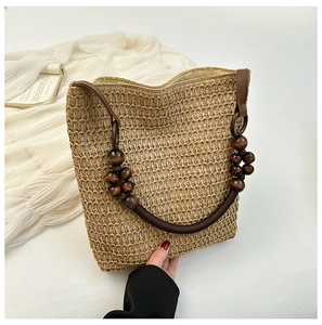 Detailed view of woven straw tote bag featuring vintage wooden bead handles and natural fiber