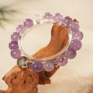 Macro detail of amethyst beaded bracelet with heart charm on natural wood background