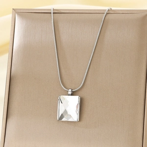 Macro shot of silver square cut crystal pendant on snake chain over silk background