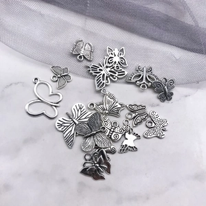 Detailed view of silver butterfly charms in various sizes on white marble surface