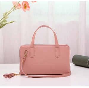 Detailed close-up of pink synthetic leather handbag with tassels and top handle