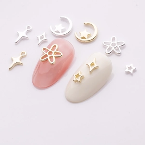 Nail art charms featuring gold and silver cross stars and moon shapes on nail tips
