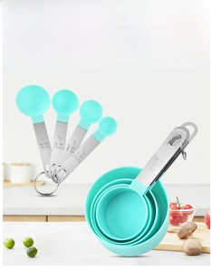 Detail of stainless steel measuring cups and spoons set with green plastic bowls