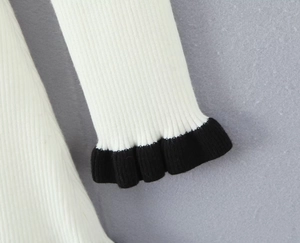 Détail du poignet de robe en maille blanche avec élégante bordure à volants noirs