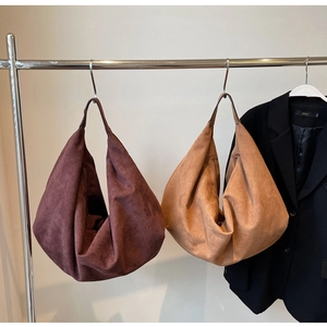 Detail view of large suede hobo bags in dark brown and light camel hanging on a rack