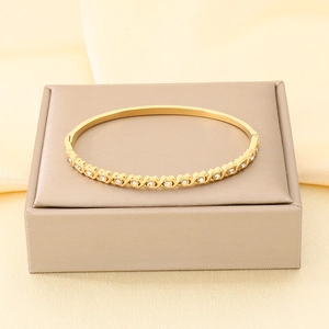 Primo piano di un bracciale in acciaio dorato con cuori e strass su una scatola regalo.