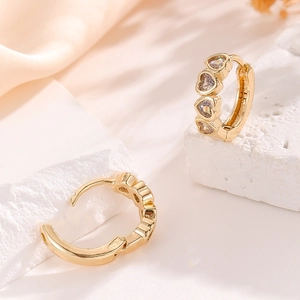 Elegant gold heart earrings with cubic zirconia stones displayed on a soft aesthetic background