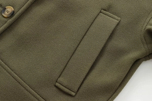 Détail d'un manteau en laine vert olive avec poche plaquée et bouton façon écaille