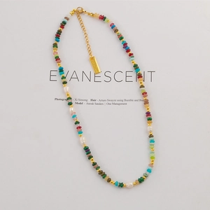 Colorful natural stone and pearl beaded necklace with gold chain on white background