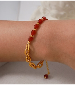 Detailed view of gold chain bracelet with red agate beads and adjustable clasp on wrist