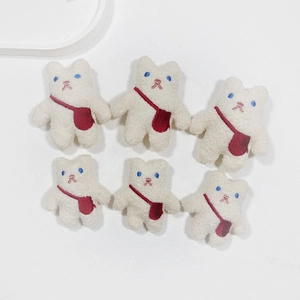 Close-up of six white plush bear patches with red crossbody bags and blue eyes