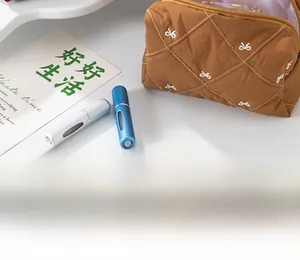 Detailed view of brown quilted cosmetic bag with white bow pattern and perfume bottles