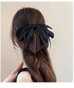 Close-up of a leopard print and black satin bow hair clip styled on long wavy hair