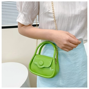 Detail of a bright green mini macaron bag with golden chain strap on a model