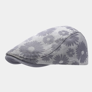 Macro detail of grey newsboy cap showing white daisy floral pattern and fabric texture