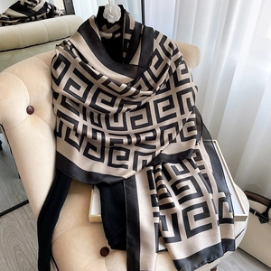 Houndstooth pattern silk scarf in beige and black draped over a soft chair