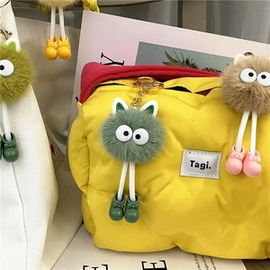 Close-up of yellow puffer bag with colorful plush coal ball charms and cute shoe details