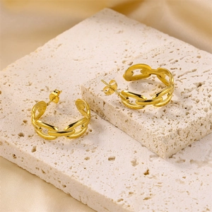 Macro detail of gold coffee bean link earrings displayed on a white textured stone base