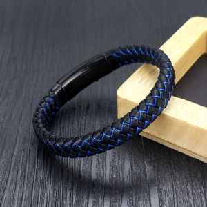 Braided leather bracelet in blue and black with black magnetic clasp on wooden background