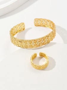 Close-up of gold-plated leaf pattern hollow cuff bracelet and ring set on white stand
