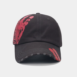 Detailed view of black cotton baseball cap featuring red graffiti and distressed brim edges