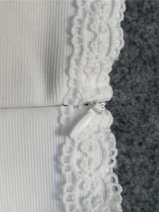 Vue macro d'une fermeture éclair invisible blanche et d'une finition en dentelle brodée