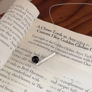 Minimalist 925 sterling silver necklace with black agate pendant on a fashion magazine