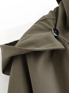Close-up of olive green trench coat showing shoulder strap button and twill fabric texture