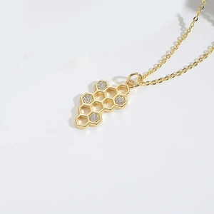 Detail of a golden necklace featuring a honeycomb pendant set with sparkling cubic zirconia