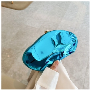Detail of blue metallic wave clutch bag with golden cylindrical clasp lock