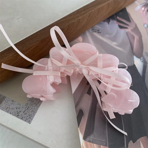 Detail of pink acetate hair claw clip with silk ribbon bow on a magazine background