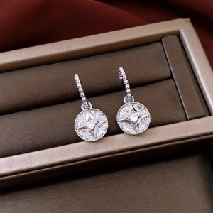 Macro detail of silver plated circular drop earrings featuring a sparkling star zircon