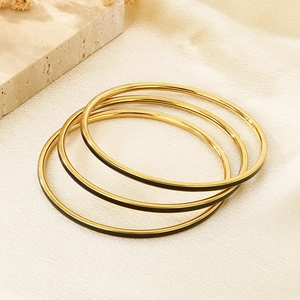 Close-up of three 3mm gold stainless steel stackable bracelets with black enamel inlay