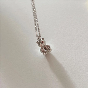 Macro detail of 3D silver bear pendant with delicate chain on a textured surface