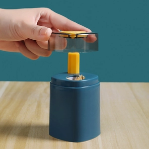 Automatic push-type toothpick dispenser in blue and yellow on a wooden desk