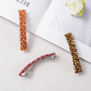 Détail de trois barrettes en perles de cristal en orange, rouge et doré bronze chic