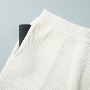 Close-up of white waffle knit shorts featuring elastic ribbed waist and side pocket details