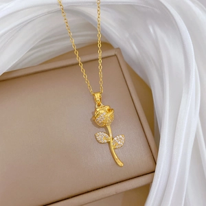 Rose flower pendant necklace with clear crystals on beige jewelry box and white veil