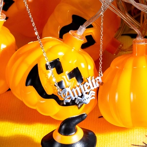 Detailed macro view of silver Angela name necklace with spider element on pumpkin background
