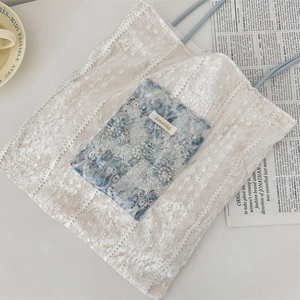 Close-up of lace embroidery details and blue floral pocket on the canvas tote bag