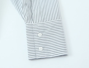 Detailed macro of blue and white striped poplin shirt cuff with dual white resin buttons