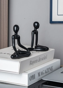 Close-up of black abstract thinking figurines on books in a modern home decor setting
