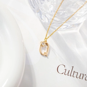 Macro detail of gold letter Q necklace pendant with micro-inlaid zircon floral accent