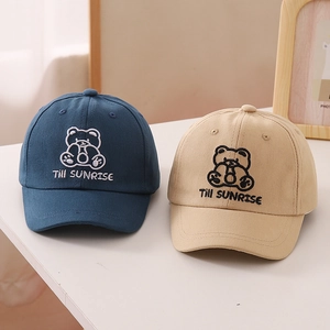 Detailed close-up of navy blue and beige cotton baseball caps with bear embroidery