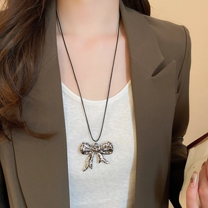 Detail of leopard print bow pendant necklace on model with black wax cord style