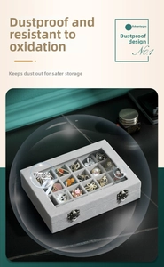 Detail view of 24-grid gray velvet jewelry box with transparent glass lid and metal buckles