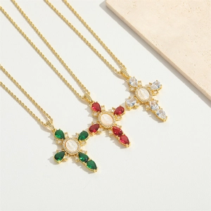 Detailed shot of three gold cross pendants with colorful stones and cameo shell centers