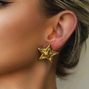Close-up of gold star stud earring on model showing metallic luster and petite design